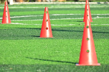 Yapay yeşil çimen futbol sahası ve turuncu eğitim konileri