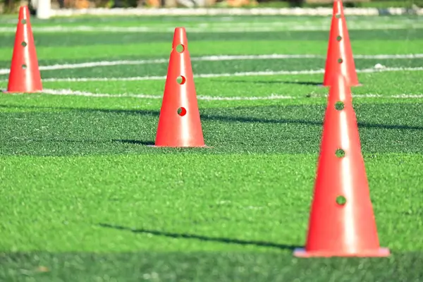 Yapay yeşil çimen futbol sahası ve turuncu eğitim konileri