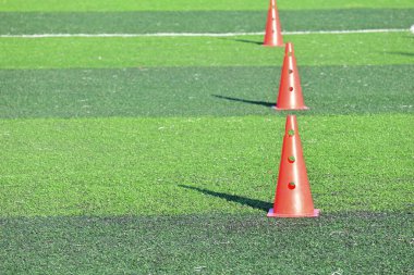 Yapay yeşil çimen futbol sahası ve turuncu eğitim konileri