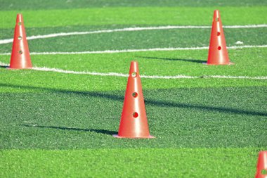 Yapay yeşil çimen futbol sahası ve turuncu eğitim konileri