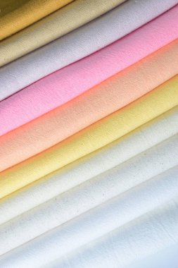 Renkli pamuklu giysiler yığını, beyaz arka planda giysi yığını