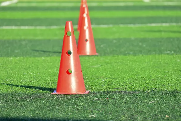 Yapay yeşil çimen futbol sahası ve turuncu eğitim konileri