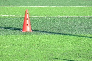 Yapay yeşil çimen futbol sahası ve turuncu eğitim konileri