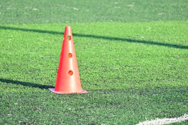 Yapay yeşil çimen futbol sahası ve turuncu eğitim konileri