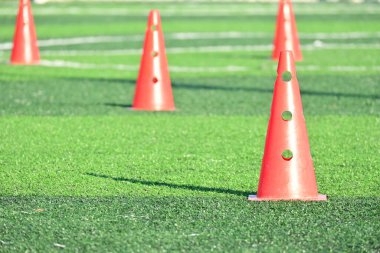 Yapay yeşil çimen futbol sahası ve turuncu eğitim konileri