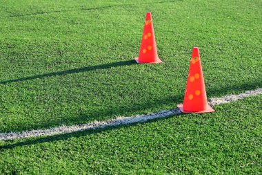 Yapay yeşil çimen futbol sahası ve turuncu eğitim konileri