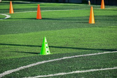 Yapay yeşil çimen futbol sahası ve turuncu eğitim konileri