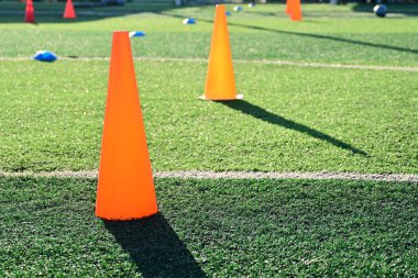 Yapay yeşil çimen futbol sahası ve turuncu eğitim konileri