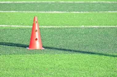 Yapay yeşil çimen futbol sahası ve turuncu eğitim konileri