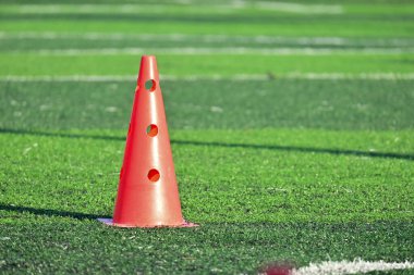 Yapay yeşil çimen futbol sahası ve turuncu eğitim konileri