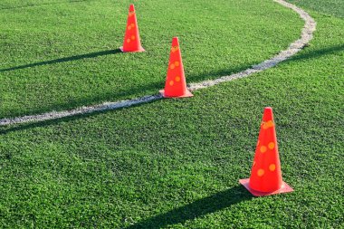 Yapay yeşil çimen futbol sahası ve turuncu eğitim konileri