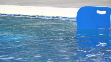 Yüzme havuzuna atlayan tatlı çocuk, gün ışığıyla birlikte suyun yüzeyinde.