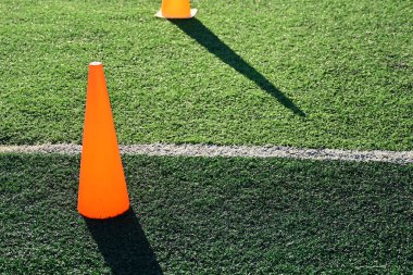 Yapay yeşil çimen futbol sahası ve turuncu eğitim konileri