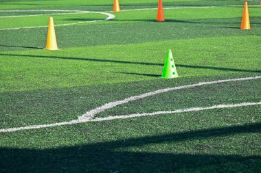 Yapay yeşil çimen futbol sahası ve turuncu eğitim konileri