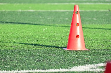 Yapay yeşil çimen futbol sahası ve turuncu eğitim konileri