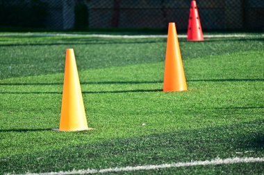 Yapay yeşil çimen futbol sahası ve turuncu eğitim konileri