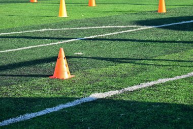 Yapay yeşil çimen futbol sahası ve turuncu eğitim konileri