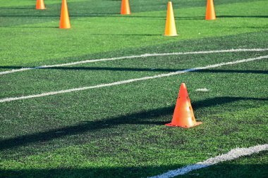 Yapay yeşil çimen futbol sahası ve turuncu eğitim konileri