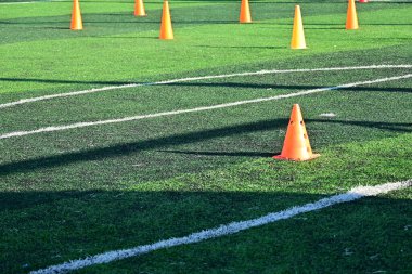 Yapay yeşil çimen futbol sahası ve turuncu eğitim konileri