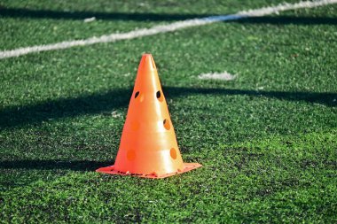 Yapay yeşil çimen futbol sahası ve turuncu eğitim konileri