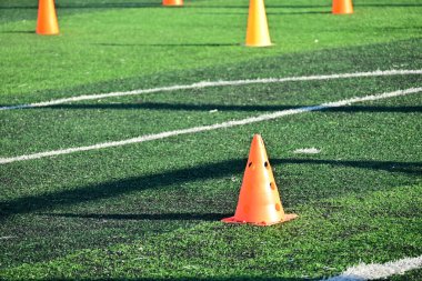 Yapay yeşil çimen futbol sahası ve turuncu eğitim konileri