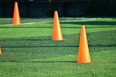 Yapay yeşil çimen futbol sahası ve turuncu eğitim konileri