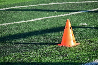 Yapay yeşil çimen futbol sahası ve turuncu eğitim konileri