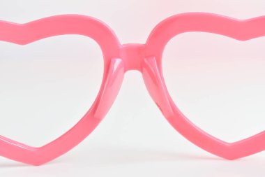 Beyaz arkaplanda pembe kalp şeklinde gözlük.