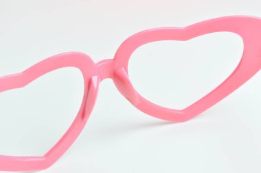 Beyaz arkaplanda pembe kalp şeklinde gözlük.