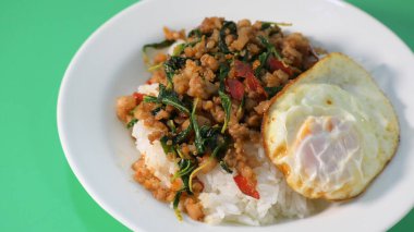 Kızarmış domuz eti, kutsal fesleğen ve pilavın üstünde kızarmış yumurta.