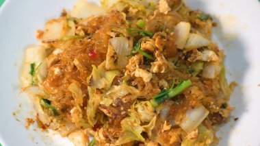 Kızarmış sukiyaki, yumurta ve domuz etini beyaz tabakta karıştırın.