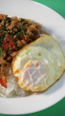 Kızarmış domuz eti, kutsal fesleğen ve pilavın üstünde kızarmış yumurta.