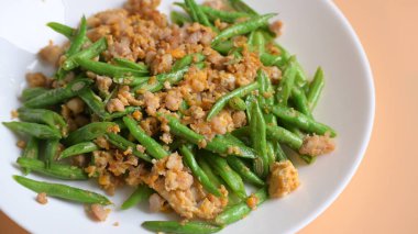 Beyaz tabakta kızarmış yeşil fasulye, Tayland yemeği ve Çin yemeği.