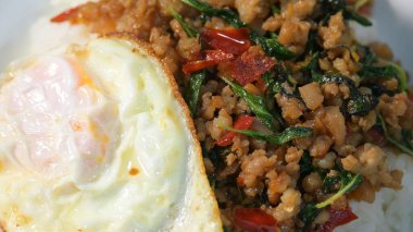 Kızarmış domuz eti, kutsal fesleğen ve pilavın üstünde kızarmış yumurta.