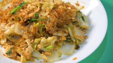 Kızarmış sukiyaki, yumurta ve domuz etini beyaz tabakta karıştırın.