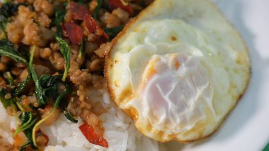 stir fried pork with holy basil on top with fried egg on cooked rice clipart