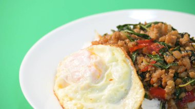 Kızarmış domuz eti, kutsal fesleğen ve pilavın üstünde kızarmış yumurta.