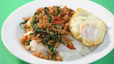 Kızarmış domuz eti, kutsal fesleğen ve pilavın üstünde kızarmış yumurta.