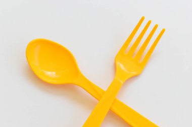 Beyaz arka planda izole edilmiş sarı kaşık ve çatal, piknik için plastik çatal bıçak.