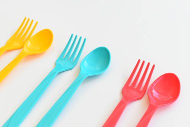 Beyaz arka planda izole edilmiş renkli kaşık ve çatal, piknik için plastik çatal