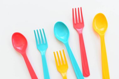 Beyaz arka planda izole edilmiş renkli kaşık ve çatal, piknik için plastik çatal