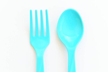 Beyaz arkaplanda mavi kaşık ve çatal, piknik için plastik çatal.
