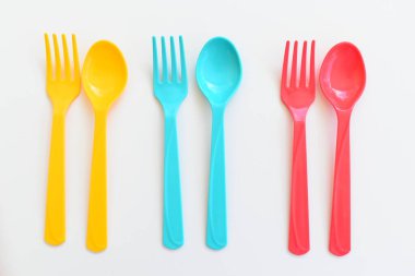 Beyaz arka planda izole edilmiş renkli kaşık ve çatal, piknik için plastik çatal