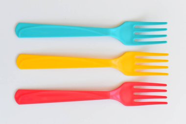 Beyaz arkaplanda renkli çatal, piknik için plastik çatal.