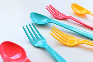 Beyaz arka planda izole edilmiş renkli kaşık ve çatal, piknik için plastik çatal