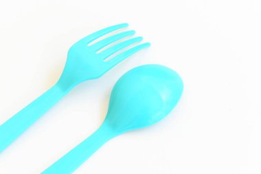 Beyaz arkaplanda mavi kaşık ve çatal, piknik için plastik çatal.