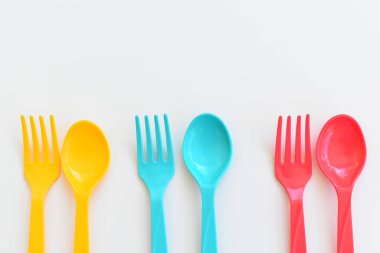 Beyaz arka planda izole edilmiş renkli kaşık ve çatal, piknik için plastik çatal