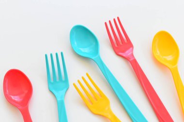 Beyaz arka planda izole edilmiş renkli kaşık ve çatal, piknik için plastik çatal