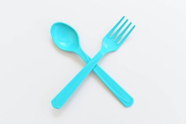 Beyaz arkaplanda mavi kaşık ve çatal, piknik için plastik çatal.