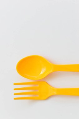 Beyaz arka planda izole edilmiş sarı kaşık ve çatal, piknik için plastik çatal bıçak.